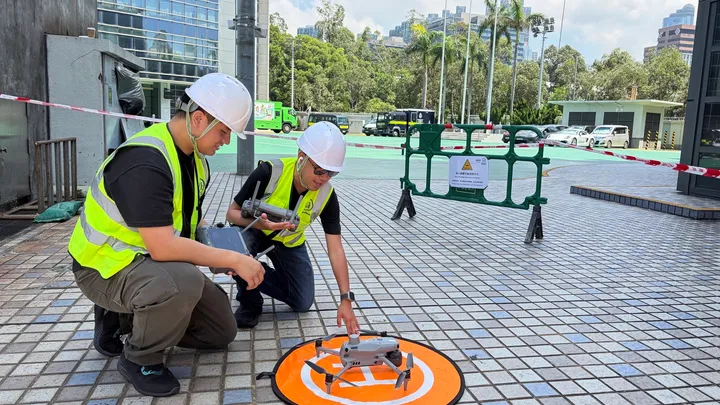 Two Swift Cruise pilots in helmets and hi-vis vests preparing a drone on a landing pad